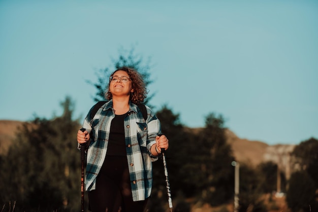 Front view of woman hiker standing outdoors in nature at sunset