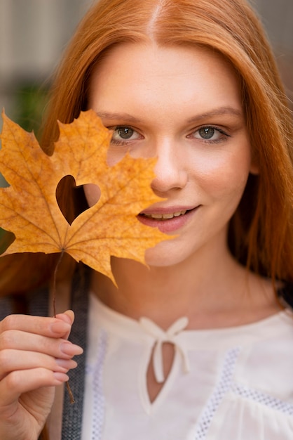 写真 ハートの形をした葉を保持している正面図の女性