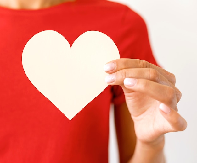 Front view of woman holding paper heart in hand