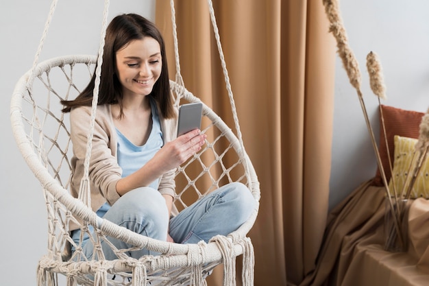 Photo front view of woman holding smartphone at home