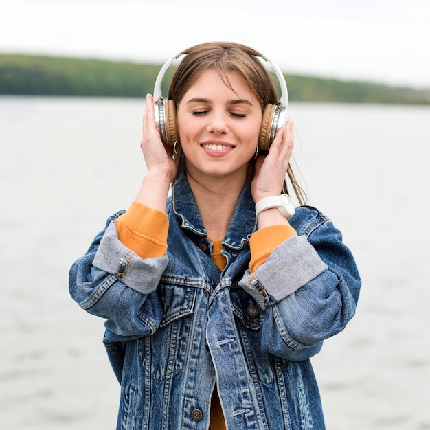 Фото Женщина вид спереди слушает музыку на берегу моря