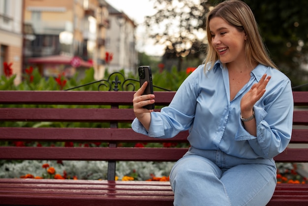 Foto donna vista frontale che effettua videochiamate con lo smartphone