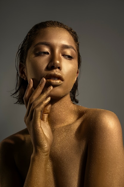 Foto donna di vista frontale che posa con la pittura del corpo dell'oro