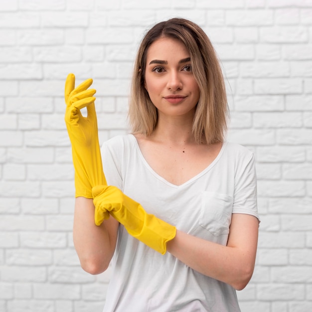 Photo front view of woman preparing to clean by putting on gloves