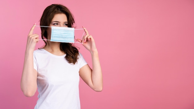 Photo front view of woman putting on medical mask