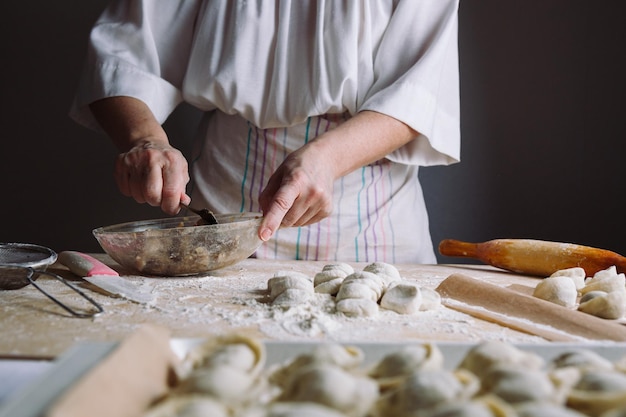 Вид спереди женских рук, делающих мясную начинку для пельменей