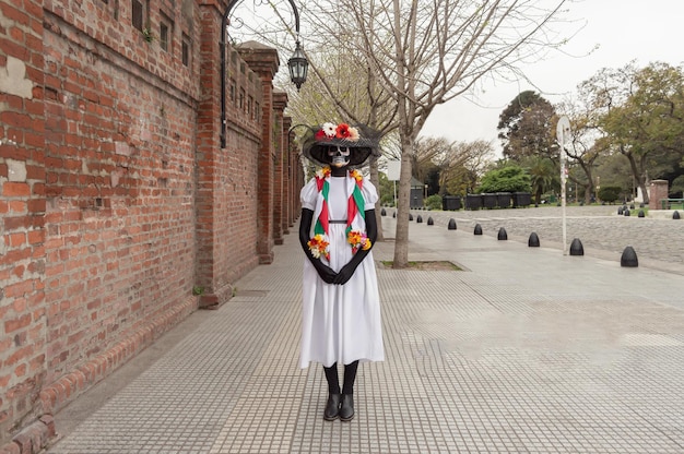 Vista frontale di una donna in piedi con le mani davanti a lei e un costume e trucco di catrina