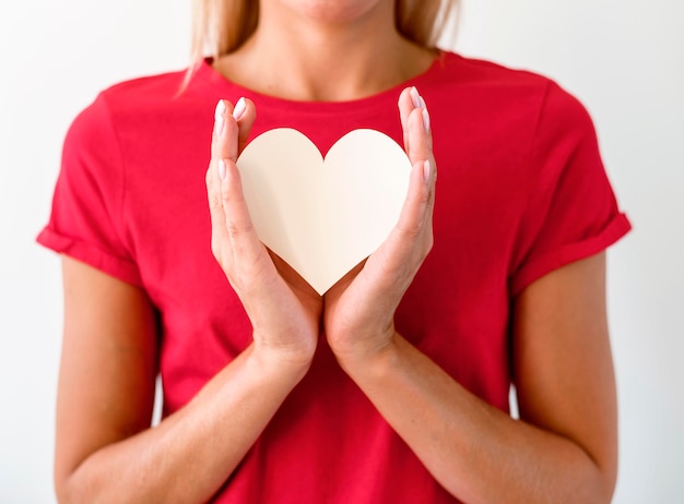 Vista frontale della donna in maglietta che tiene il cuore di carta