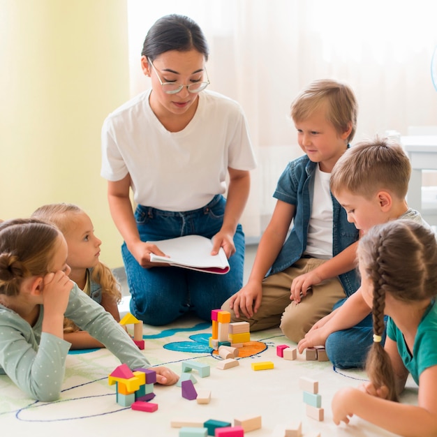 Photo front view woman teaching kids in kindergarten