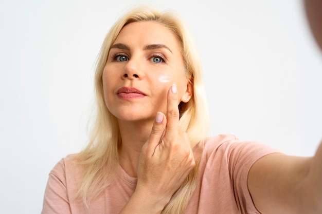 Photo front view woman using face cream