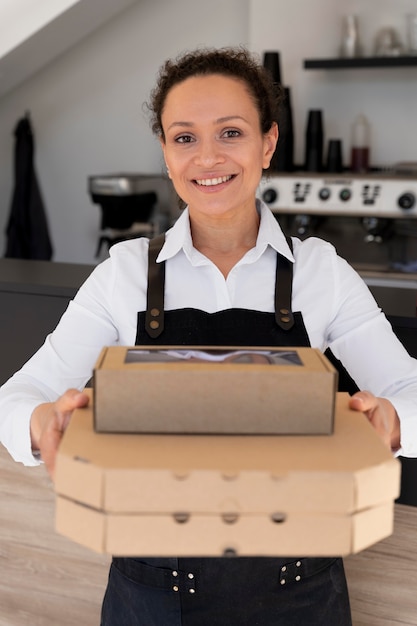 Front view of woman wearing apron holding packed takeaway food