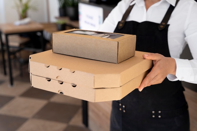 Photo front view of woman wearing apron holding packed takeaway food