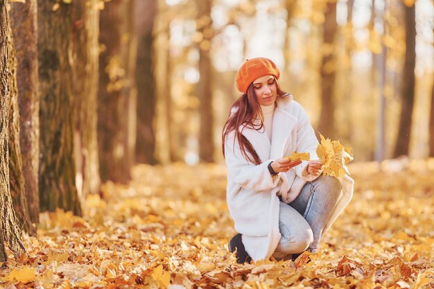 Front view Woman in white coat having fun in the autumn park