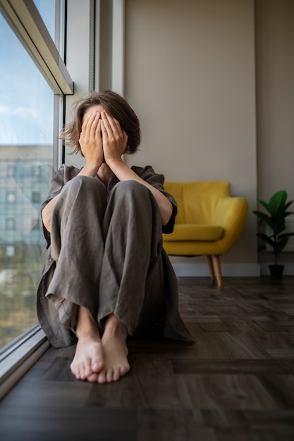 Front view woman with anxiety sitting on floor