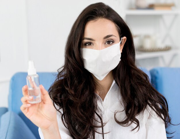 Vista frontale della donna con disinfettante per le mani della tenuta della maschera