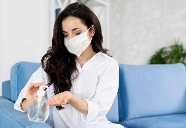 Foto vista frontale della donna con la maschera per il viso che disinfetta la sua mano