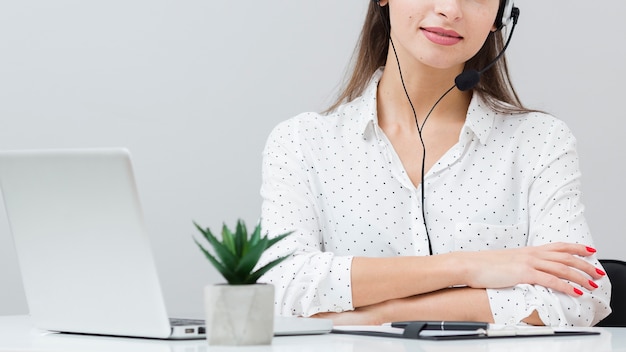 Vista frontale della donna con la cuffia avricolare che posa allo scrittorio