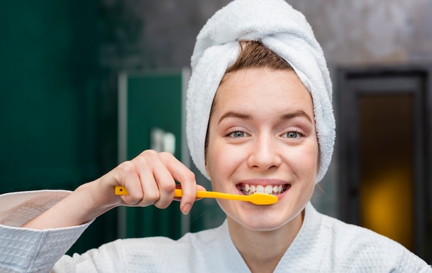 Photo front view of woman with towel brushing her teeth