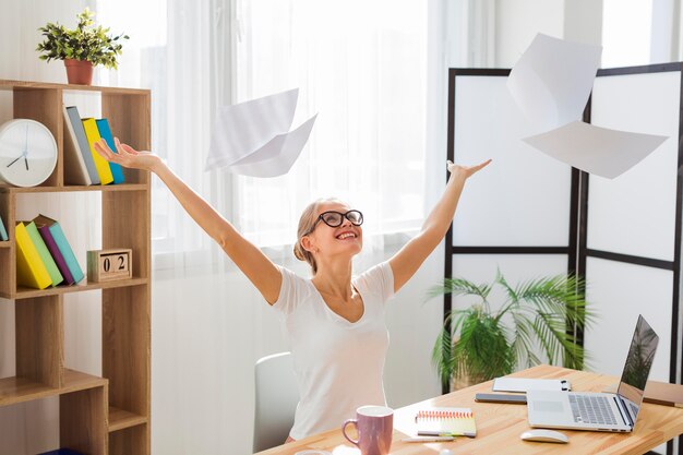 Photo front view of woman working from home and throwing papers in the air