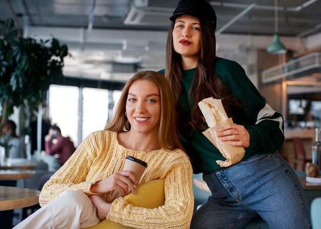 Photo front view women holding  paper-wrapped sandwich