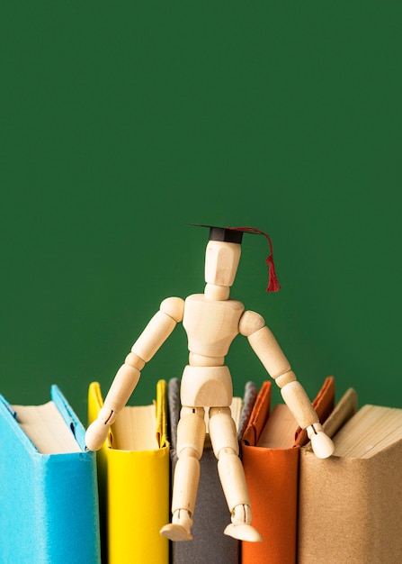 Photo front view of wooden figurine with books and copy space