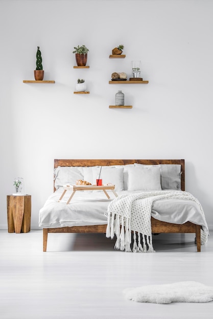 Front view of a wooden framed double bed with linen pillows and