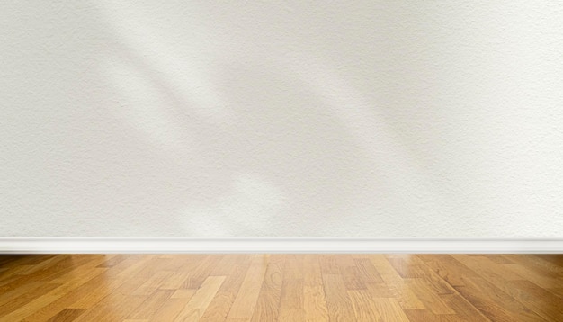 Vista frontale del pavimento in parquet di legno e parete beige chiaro vuota con ombre astratte