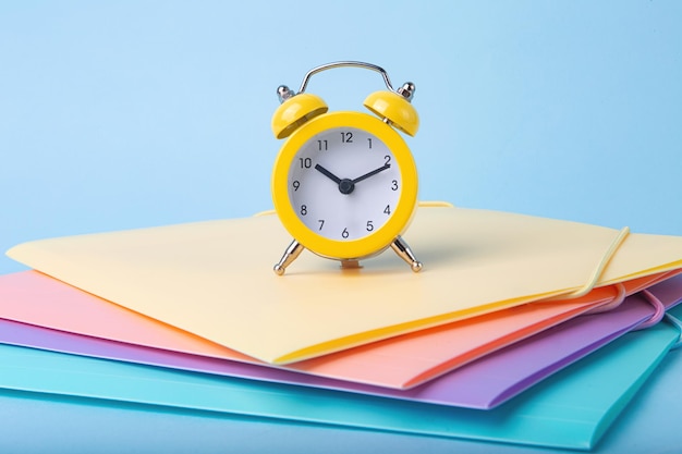 front view of yellow alarm clock staying on foldersback to school concept