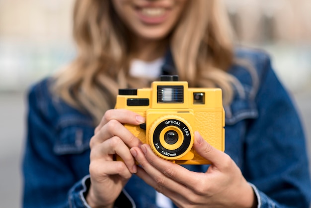 Macchina fotografica gialla di vista frontale e donna vaga