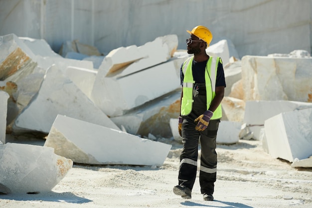 Vista frontale del giovane ingegnere maschio afroamericano in uniforme e casco di sicurezza