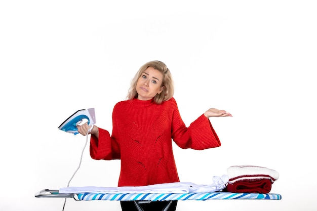 Photo front view of young beautiful woman holding iron and feeling unsure about something on white background