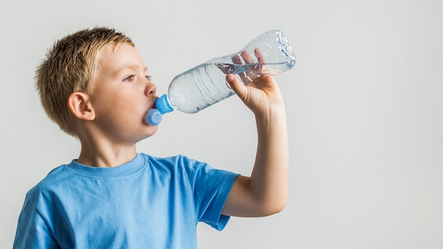 Front view young boy drinking water