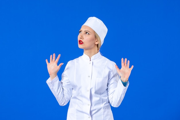 front view of young coquette nurse in medical suit on blue background drug pandemic covid- disease virus medicine hospital illness health