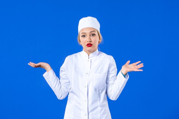 front view of young coquette nurse in medical suit on blue background drug pandemic covid- medicine hospital illness disease health