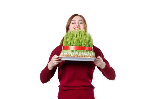 흰색 배경에 큰 녹색 novruz semeni를 들고 전면 보기 젊은 여성 봄 민족 수행자 민족 개념 색상 가족