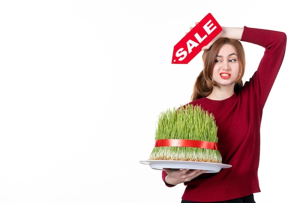 front view young female holding big novruz semeni and red sale nameplate on white background diner colours performer ethnicity concept shopping spring ethnic