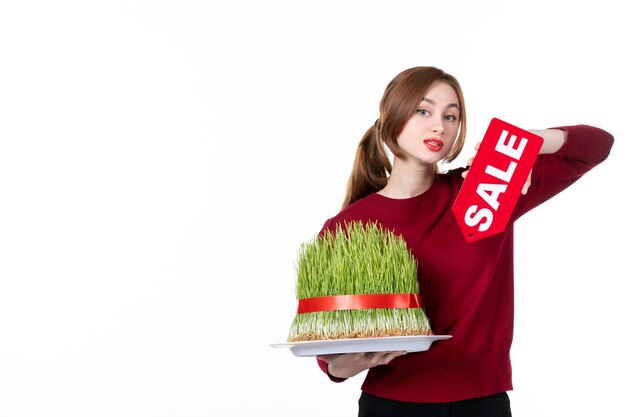 正面図白い背景の上の大きなnovruzsemeniと赤い販売ネームプレートを保持している若い女性ダイナーパフォーマー民族コンセプトショッピング