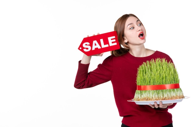 front view young female holding big novruz semeni and sale nameplate on white background concept ethnicity family shopping performers ethnic spring colours