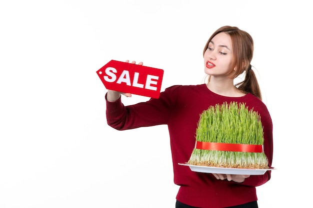 front view young female holding big novruz semeni and sale nameplate on white background spring colours ethnicity shopping family concept performer