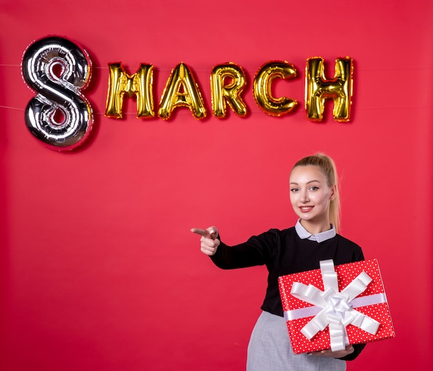 front view young female holding present with march decoration pointing on red background passion womans day luxurious equality feminine money