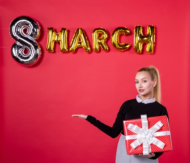 front view young female holding present with march decoration on red background passion salon womans day luxurious equality feminine shopping money