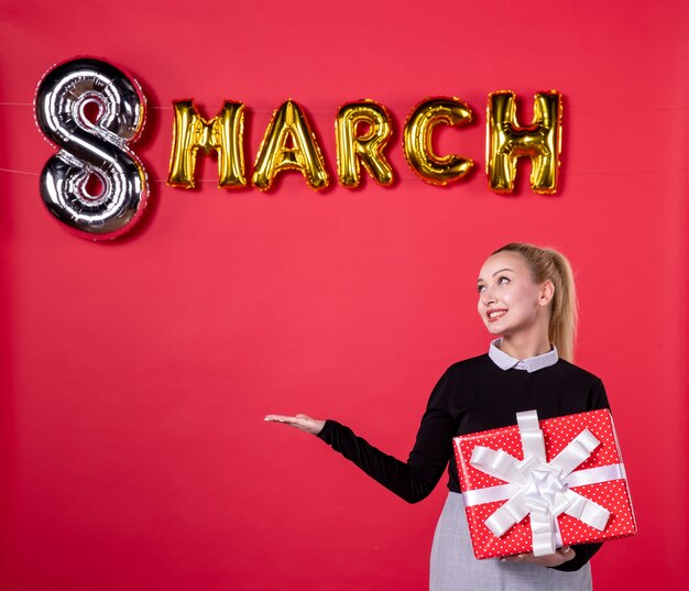 front view young female holding present with march decoration on red background passion womans day luxurious equality feminine shopping money