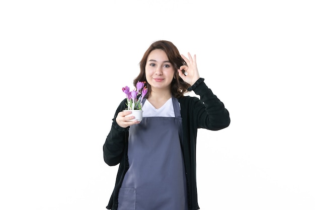 front view young female holding purple flowers on light background soil nature uniform tree emotion garden green woman flowers pot