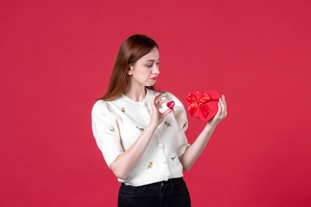 front view young female holding red heart shaped present on red background marriage womens day sensual march equality fashion feminine love