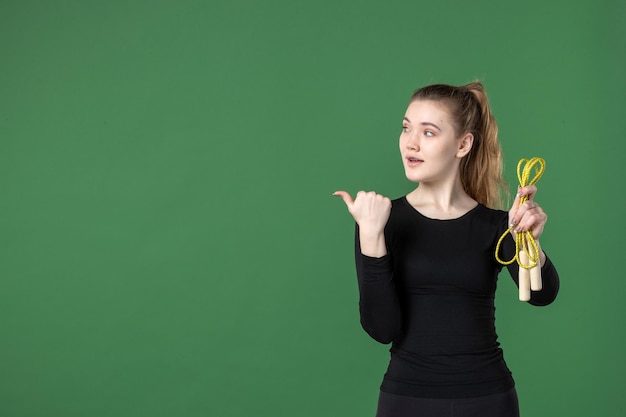 Front view young female holding skipping rope on green background health woman workout color sport athlete body