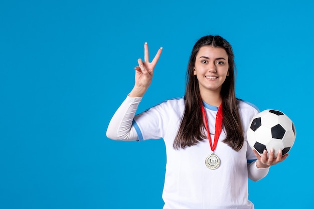 Front view young female holding soccer ball on blue wall