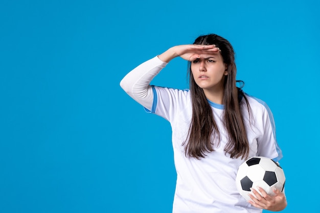 Front view young female holding soccer ball on blue wall