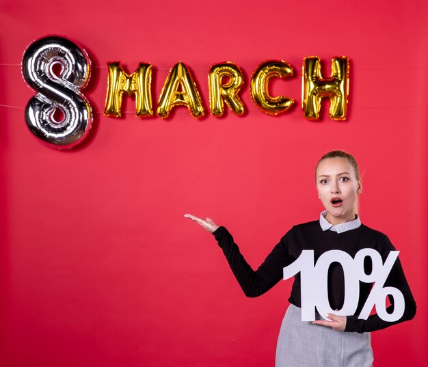 Foto vista frontale giovane donna che tiene la scrittura con decorazione di marzo su sfondo rosso shopping femminile giorno della donna passione uguaglianza salone lussuoso