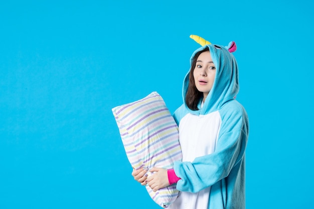 front view young female in kigurumi for pajama party hugging pillow on blue background cartoon dream sleep friends game night fun color late bed