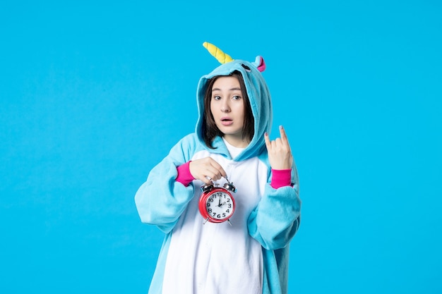 front view young female in pajama party holding clocks on blue background late dream rest bed nightmare sleep night game time woman